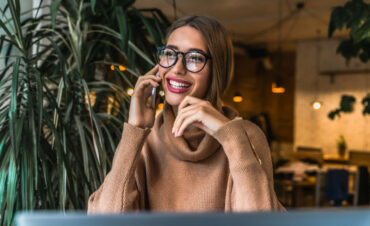 Beautiful young businesswoman sitting at cafe and having telephone conversation with client Beautiful young businesswoman sitting at cafe and having telephone conversation with client
